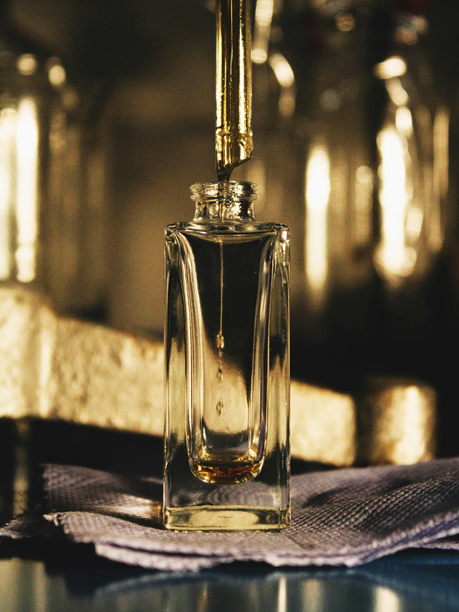 A glass perfume bottle being filled with fragrance