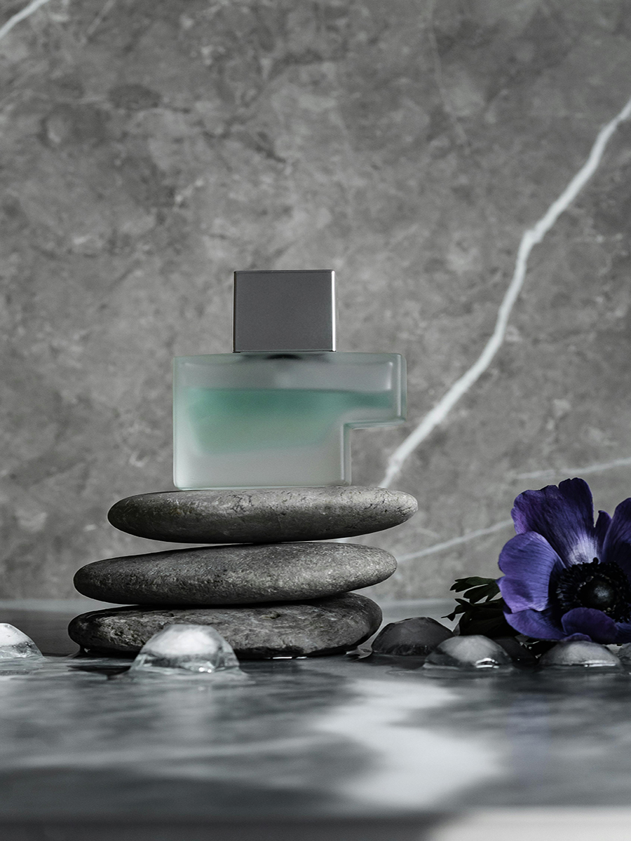 perfume bottle with stones and flower with the gray background